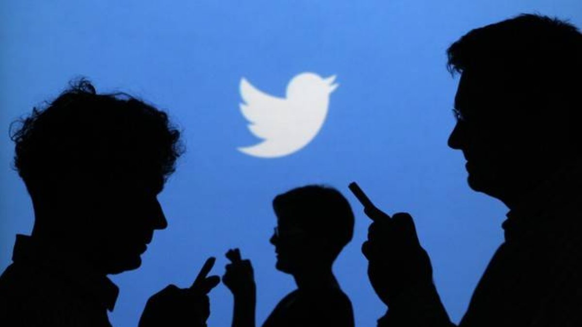 Siluetas de gente con el móvil, con el logo de Twitter al fondo.-REUTERS