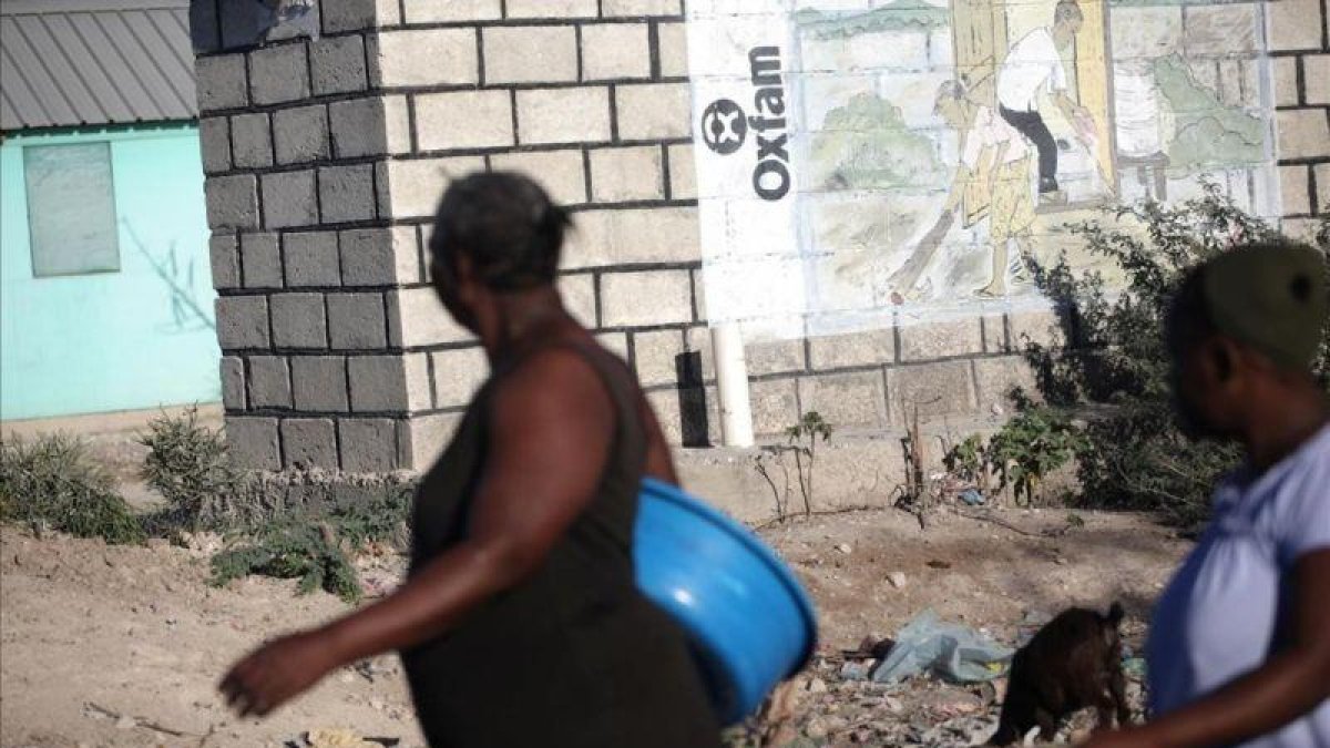 Dos mujeres pasan ante un mural de Oxfam en Puerto Príncipe, Haití.-ANDRES MARTINEZ CASARES (REUTERS)