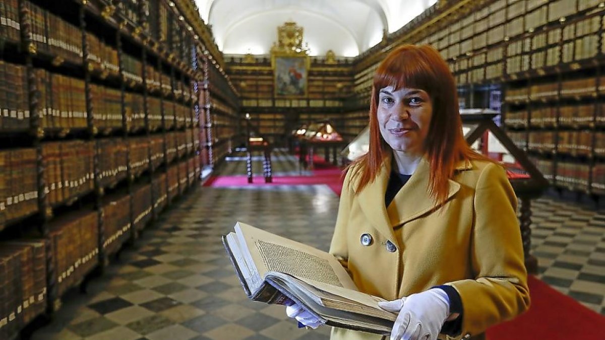 Ane E. Galindo Azkunaga, con un volumen de los fondos de la Biblioteca Histórica de Santa Cruz, y portada de su libro.-J.M. LOSTAU