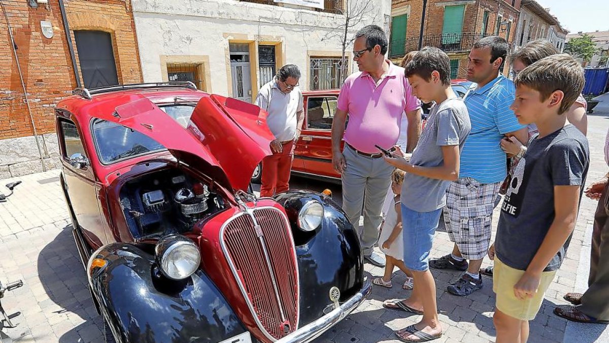 Viandantes contemplan en Cigales el premio al Coche más Antiguo, un Fiat 1100 del año 1936.-J.M. Lostau