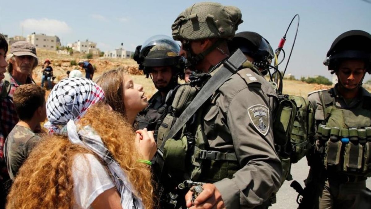 Ahed Tamimi se enfrenta a dos soldados israelís en la localidad de Nabi Saleh, en Cisjordania.-AFP / ABBAS MOMANI