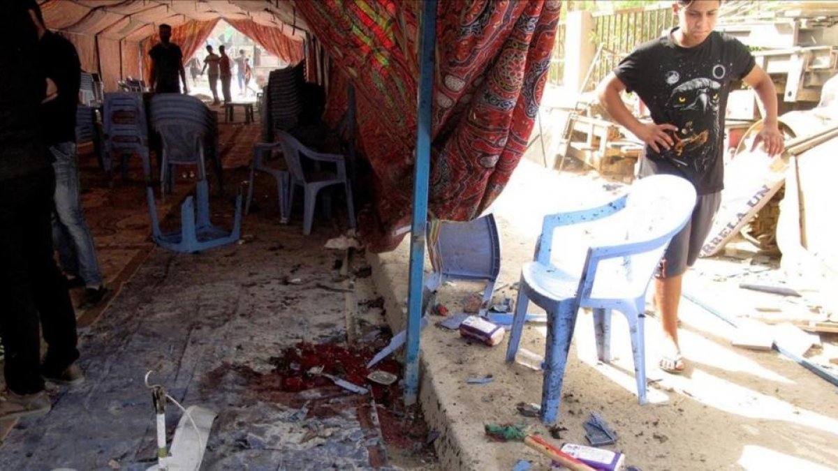 Varios iraquís inspeccionan la tienda donde se ha cometido el atentado suicida, en el barrio de Shaab, en Bagdad, este sábado.-EFE / ALI ABBAS
