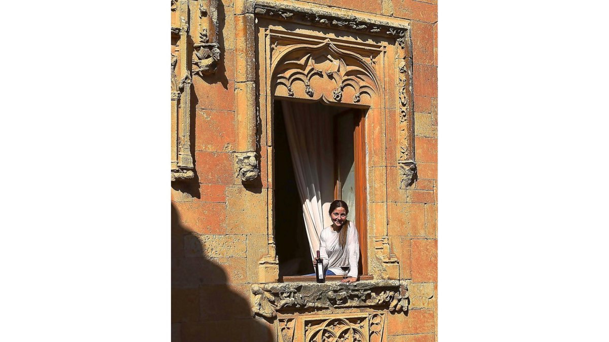 Pilar Fernández de Trocóniz, en la denominada Ventana del Obispo, que corona el patio del Castillo del Buen Amor, con su tinto CBA. En la foto pequeña, los viñedos que rodean el Castillo del Buen Amor, con la torre del homenaje al fondo.-ARGI