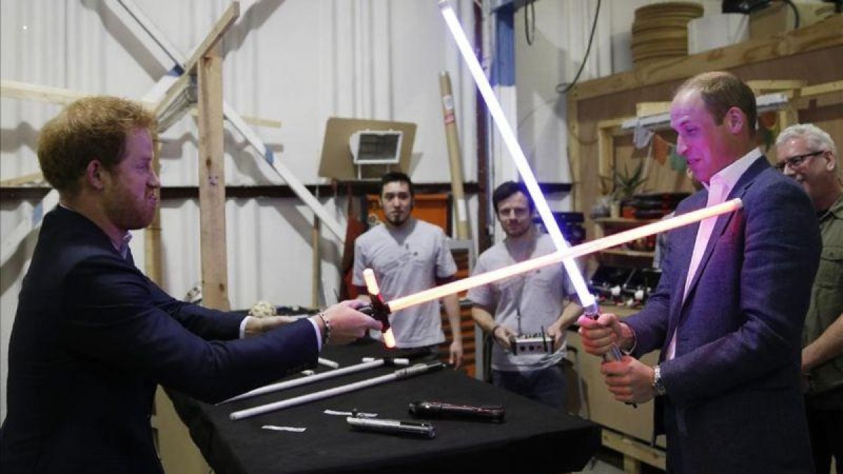 Los príncipes Enrique y Guillermo juegan con las espadas de luz de Star Wars en su visita a los estudios de Londres donde se está rodando la octava entrega de la saga.-EL PERIÓDICO (AP / ADRIAN DENNIS)