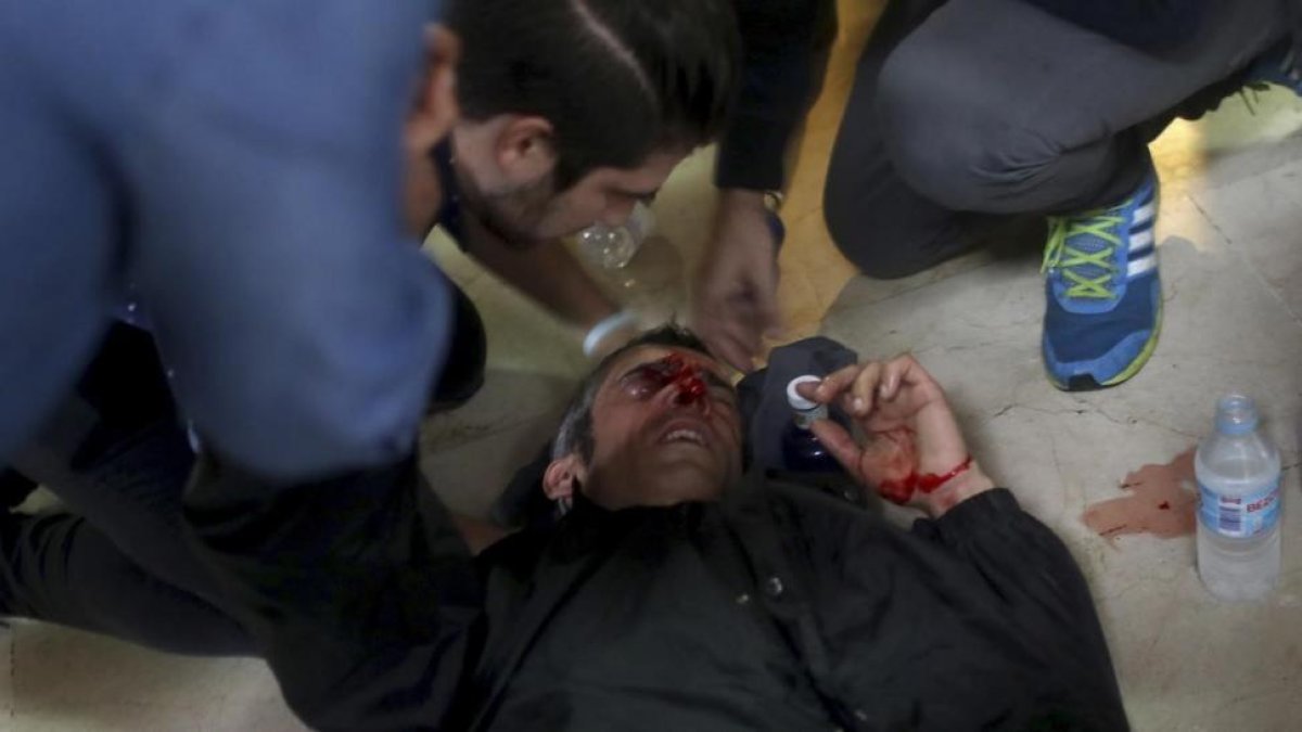 Un manifestante es atendido después de ser golpeado por una bala de goma disparada en la escuela Ramón Llull.-MANU BRABO/AP