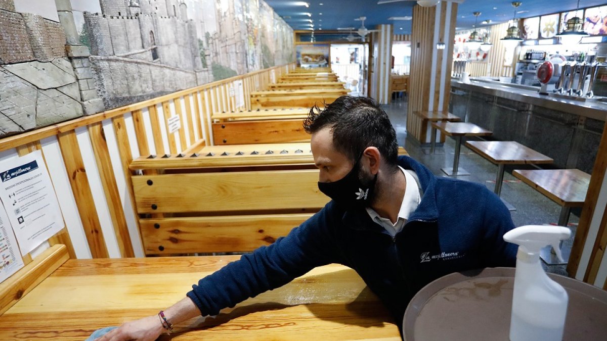Un trabajador limpia las mesas del interior del restaurante La Mejillonera. | J.M. LOSTAU