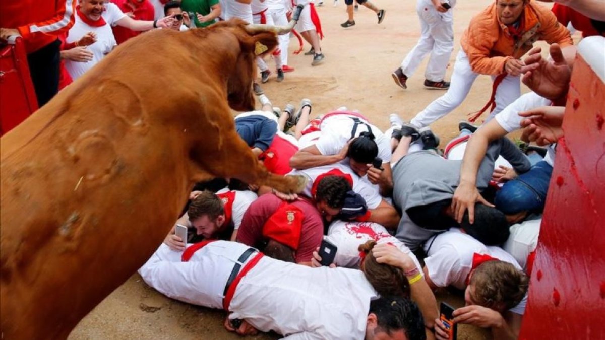 Un grupo de mozos grabando cómo les pasa una vaquilla por encima.-SUSANA VERA / REUTERS