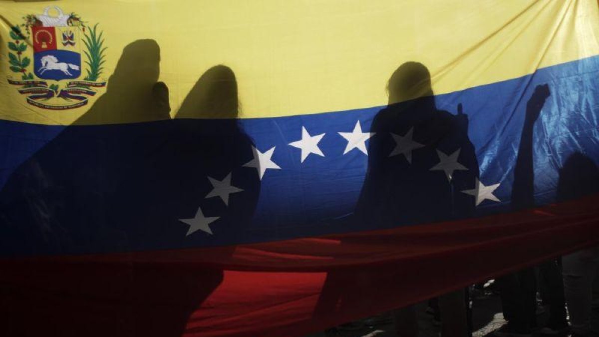 La bandera venezolana, entre sombras en una protesta en Costa Rica.-EFE/JEFFREY ARGUEDAS