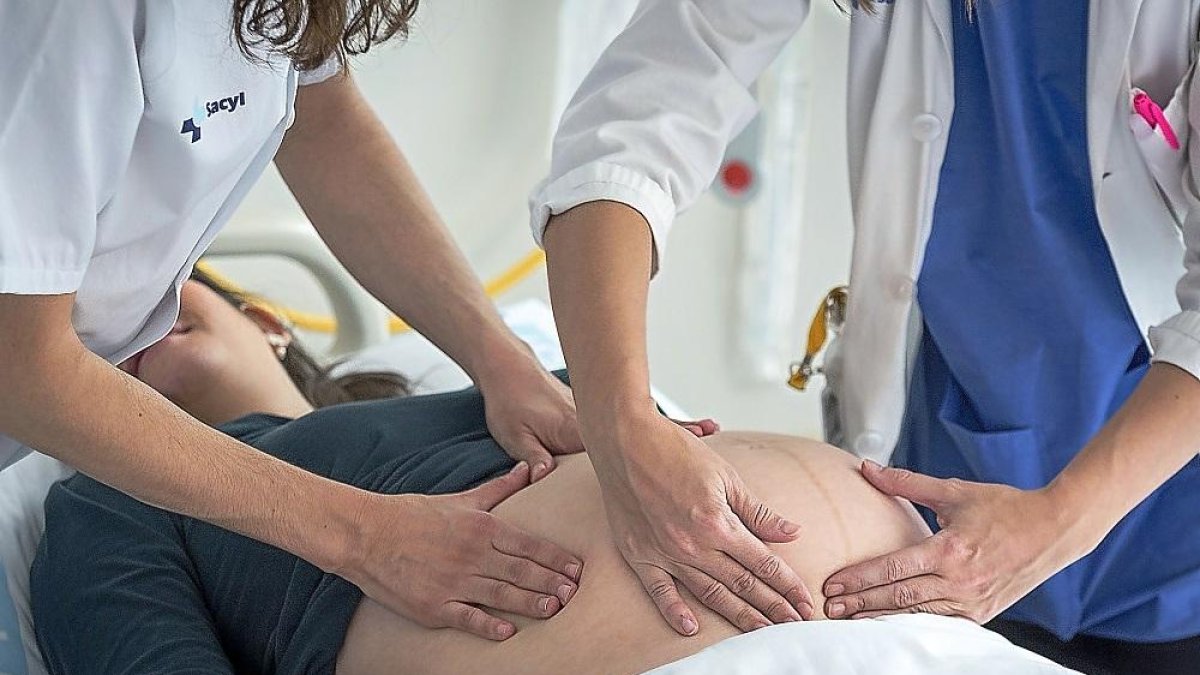 Una mujer embarazada junto a una enfermera y una médico en una revisión-E. M.