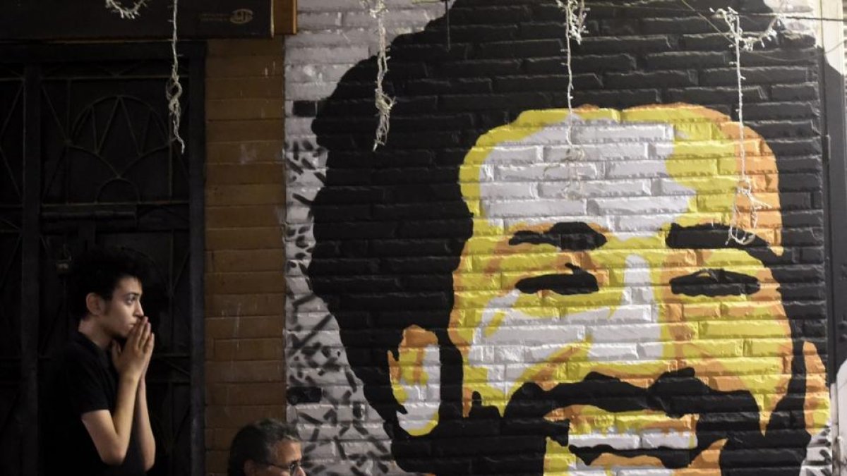 Un aficionado egipcio muestra su preocupación en El Cairo tras lesionarse Salah junto a una pintura del delantero.-AFP