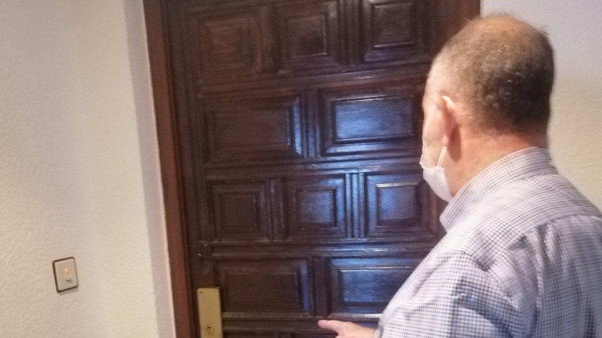 Un vecino señala la puerta del domicilio del fallecido.- E. M.