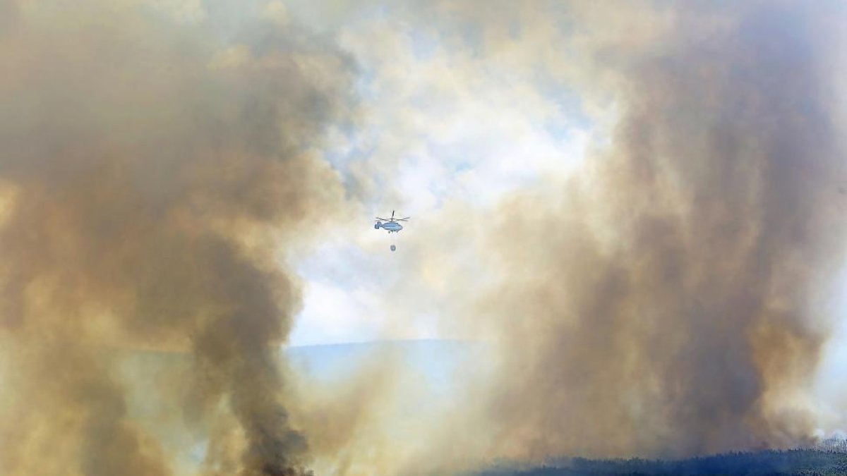Un helicóptero durante las labores de extinción del incendio que desde el lunes permanece activo en Encinedo, en la comarca de La Cabrera..-ICAL