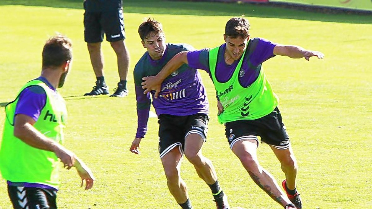 Mata conduce el balón mientras aparta con la mano a Markel, durante un entrenamiento.-J.M.LOSTAU