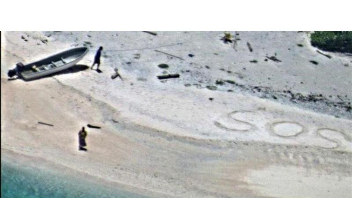 SOS escrito en la arena de playa por Linus y Sabina Jack.-US NAVY