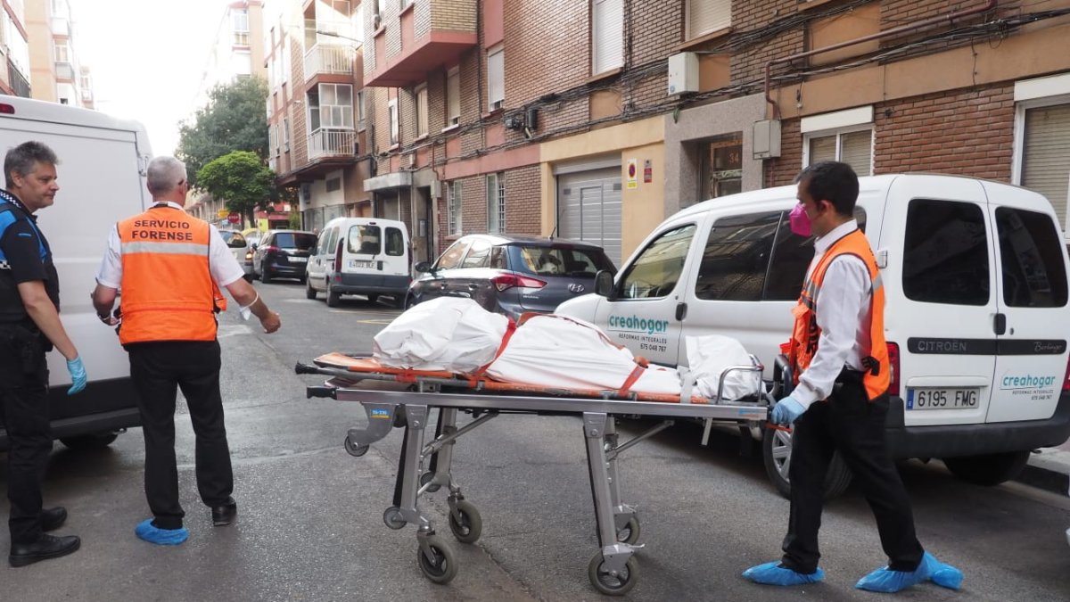 Dos operarios sacan a uno de los cadáveres del edificio en la calle Linares.- E.M.