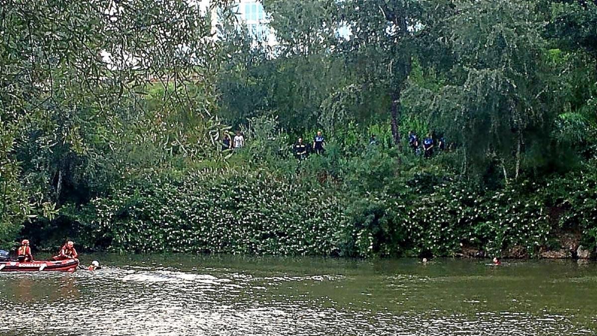 Varios agentes observan desde la orilla la lancha de Bomberos y el joven, a la derecha, en al zona de Curtidores.-E. M.