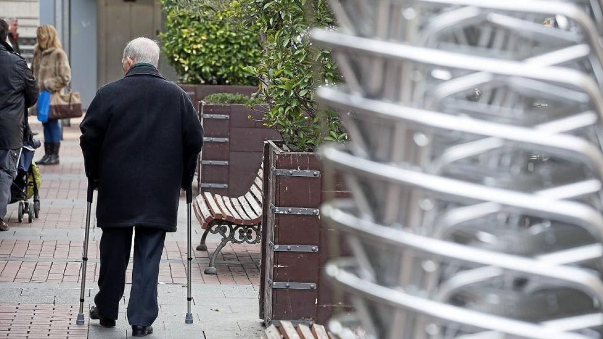 Un anciano pasea por una calle de Valladolid apoyado en dos muletas.-EL MUNDO