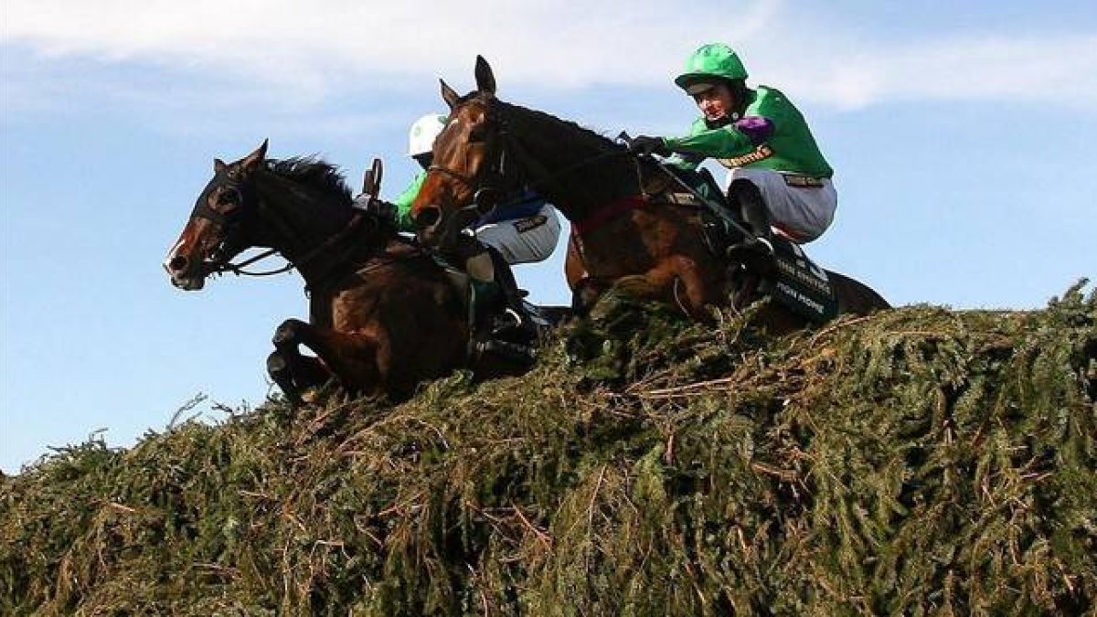 Dos caballos con sus respectivos jinetes saltan un obstáculo en el Grand National de Aintree, en el 2009.-Foto: PETER BYRNE