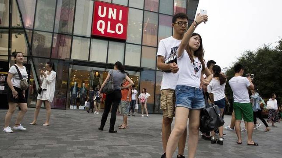 Una pareja de jóvenes se hacen un seli frente a la cadena de ropa Uniqlo, en Pekín.-Foto: AP