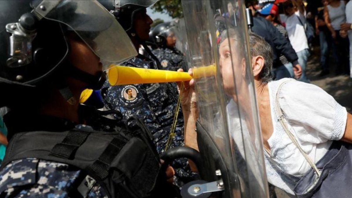 Una manifestantes de la oposición se encara con los antidisturbios en la protesta de este sábado en Caracas.-REUTERS / CARLOS GARCÍA RAWLINS