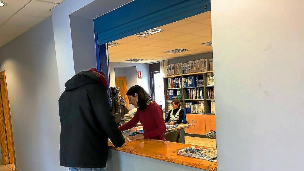 Un vecino se acerca a la administración del Ayuntamiento donde se realizan los trámites. A la derecha, simulación del carné.-A.R.E.