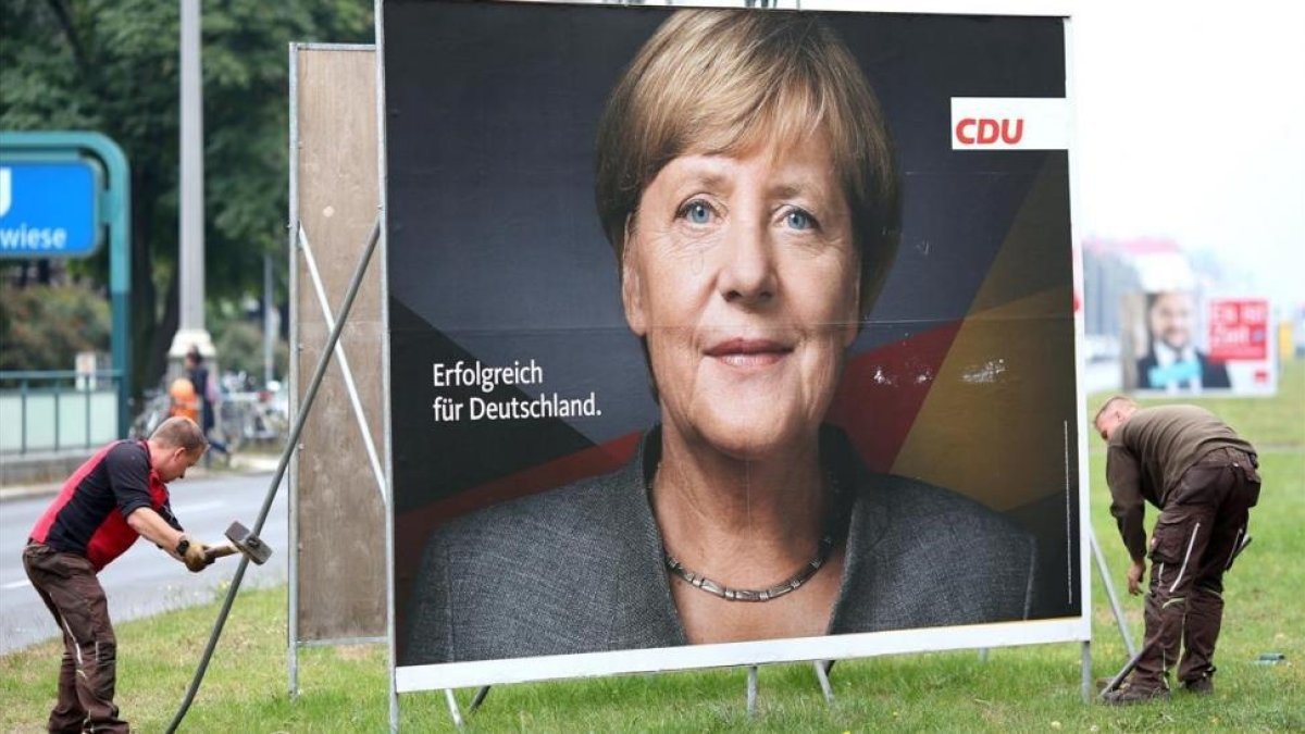 Retirada de un cartel electoral de Angela Merkel en Berlín-REUTERS / CHRISTIAN MANG