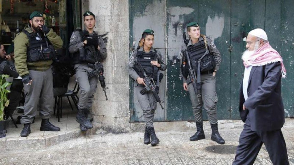 Un palestino camina ante un grupo de soldados israelís en la ciudad antigua de Jerusalén.-THOMAS COEX / AFP