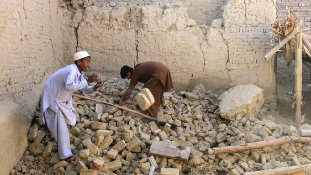 Dos niños afganos mueven los escombros de su vivienda, en el distrito de Nangarhar.-REUTERS / PARWIZ