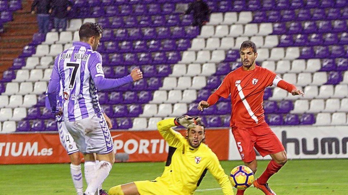 Juan Villar observa la trayectoria del balón, que avanza hacia la portería del Sevilla Atlético sin que Caro pueda hacer nada por evitar el 1-0.-J.M.LOSTAU