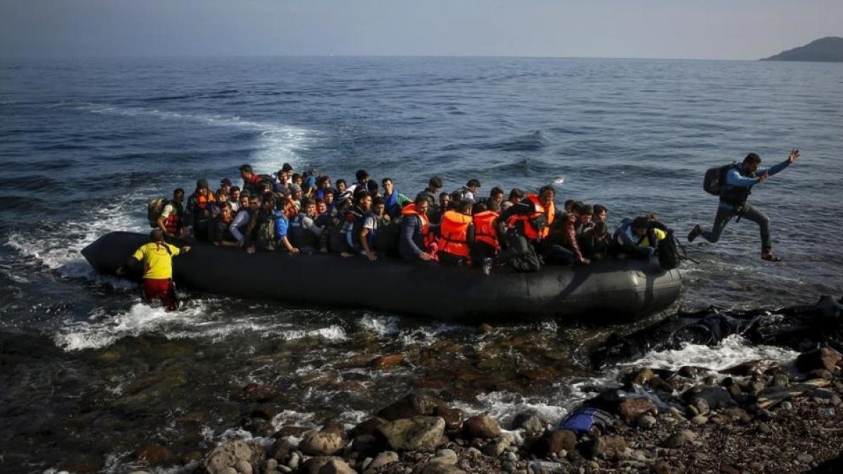 Un migrante afgano salta de una sobresaturada patera al alcanzar la playa en Lesbos (Grecia), el 19 de octubre del 2015.-YANNIS BEHRAKIS