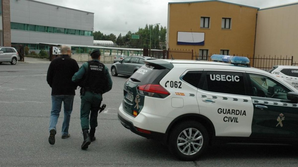Un guardia civil se lleva detenido a uno de los implicados.-GUARDIA CIVIL