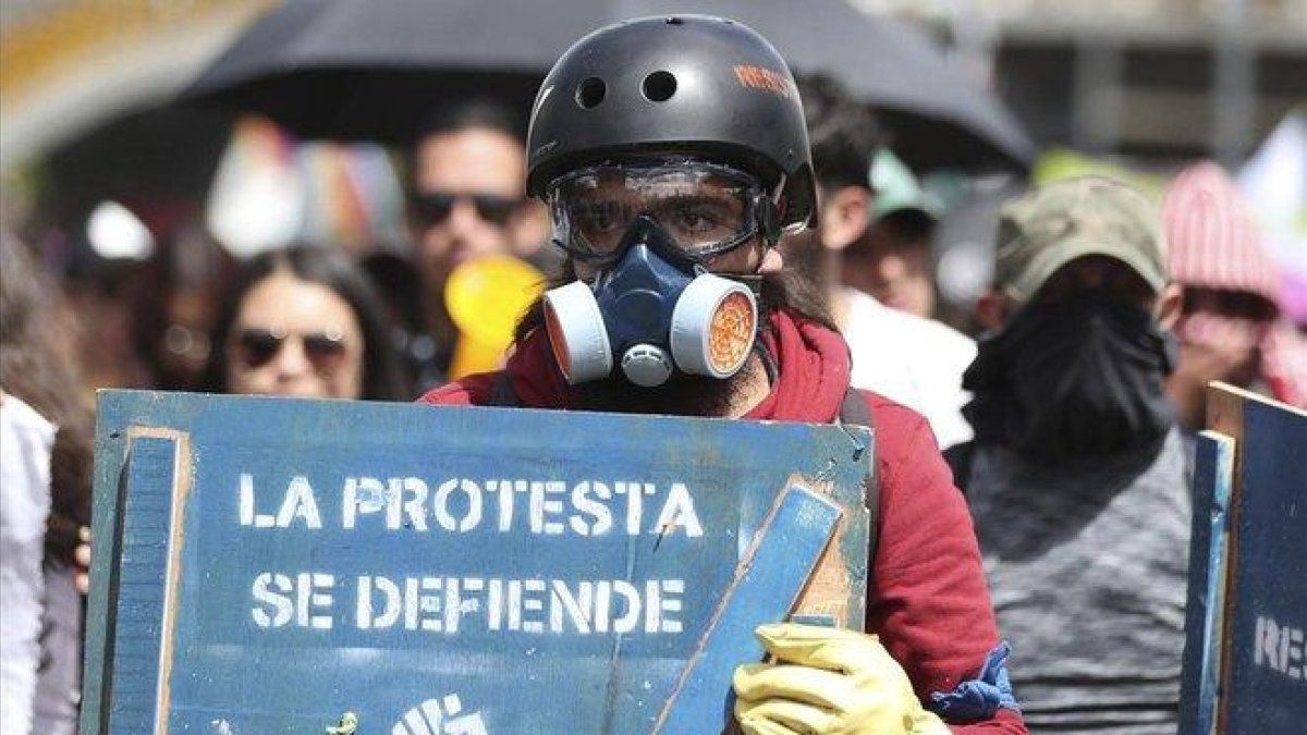 Una manifestante sostiene un cartel de protesta en una marcha en Bogotá contra el Gobierno de Duque.-FERNANDO VERGARA (AP)