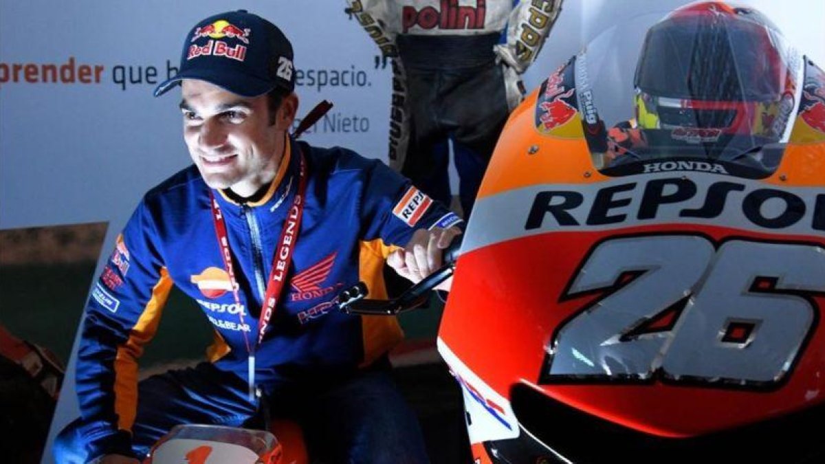Dani Pedrosa se ha fotografiado hoy, en Valencia, el día de su adios, con una moto de juguete y su Honda RC213V nº 26.-AFP / JOSÉ JORDAN