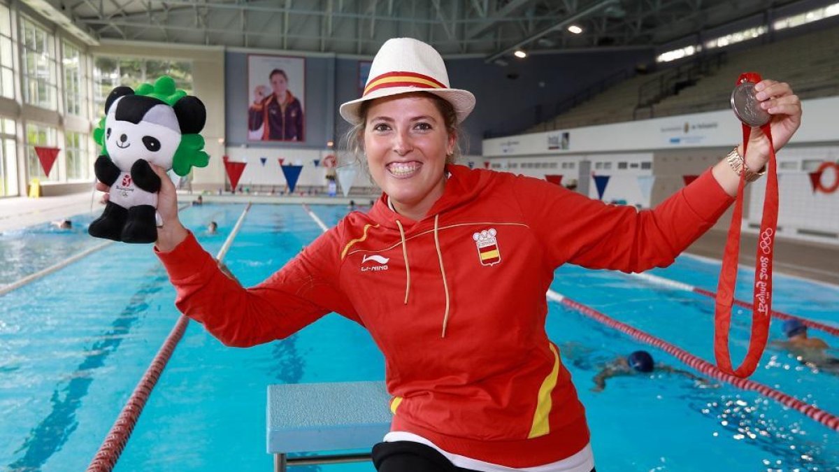 Laura López Valle posa en la piscina de Huerta del Rey -con su foto al fondo- con sus recuerdos de Beijin 2008, la mascota Jingjing y la medalla de plata.-J. M. LOSTAU