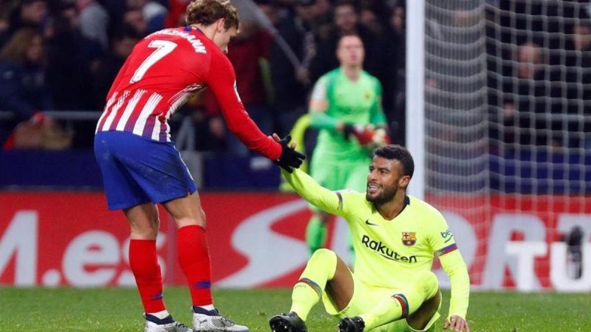 Griezmann ayuda a Rafinha a levantarse en la segunda parte del Atlético-Barça en el Metropolitano.-REUTERS / PAUL HANNA