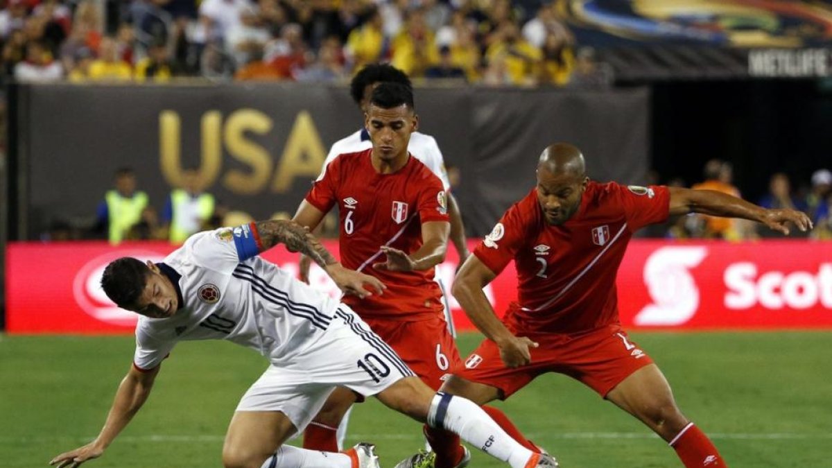 El colombiano James Rodriguez pugna por el balón con los peruanos Alberto Rodriguez y Miguel Trauco.-EFE / JASON SZENES