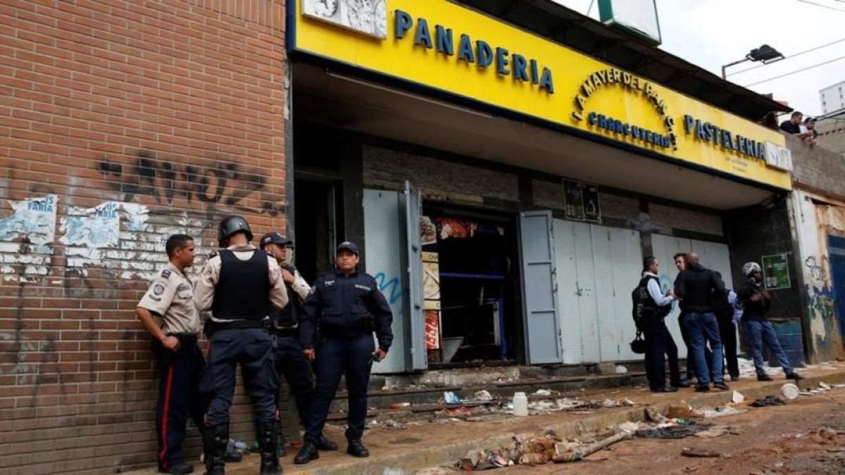 Agentes de policía frente a la panadería asaltada en Caracas, el 21 de abril.-REUTERS / CARLOS GARCIA RAWLINS