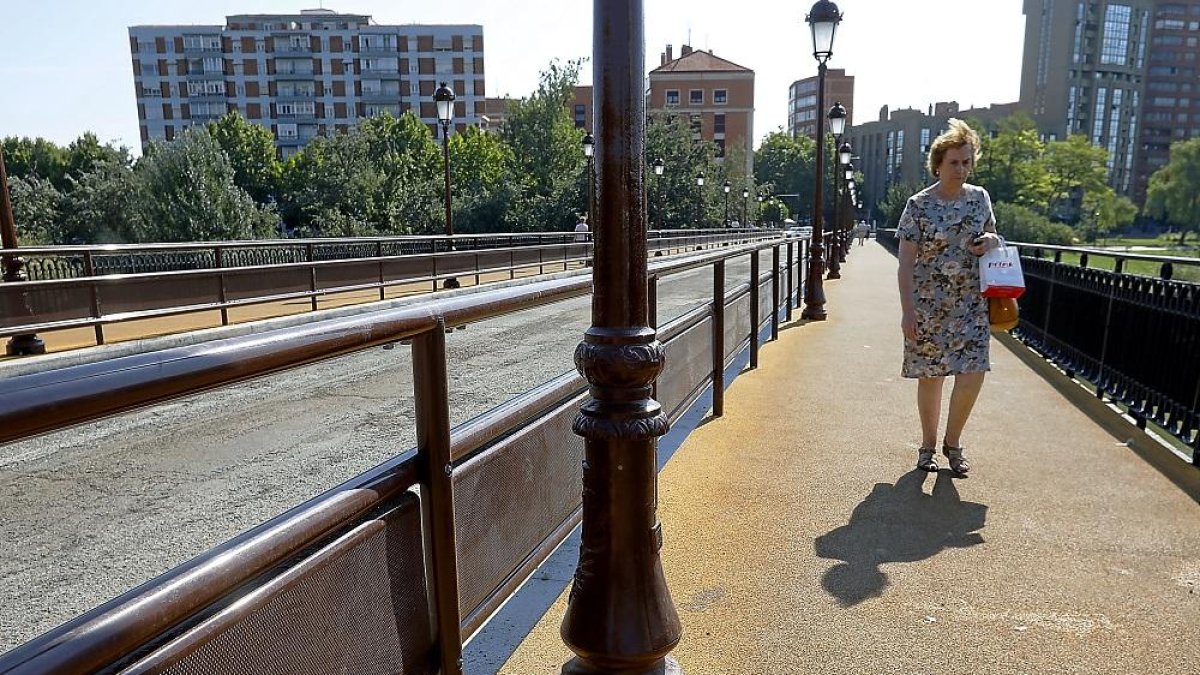 Una señora recorre el puente sobre las nuevas aceras de caucho instaladas.-J.M. LOSTAU