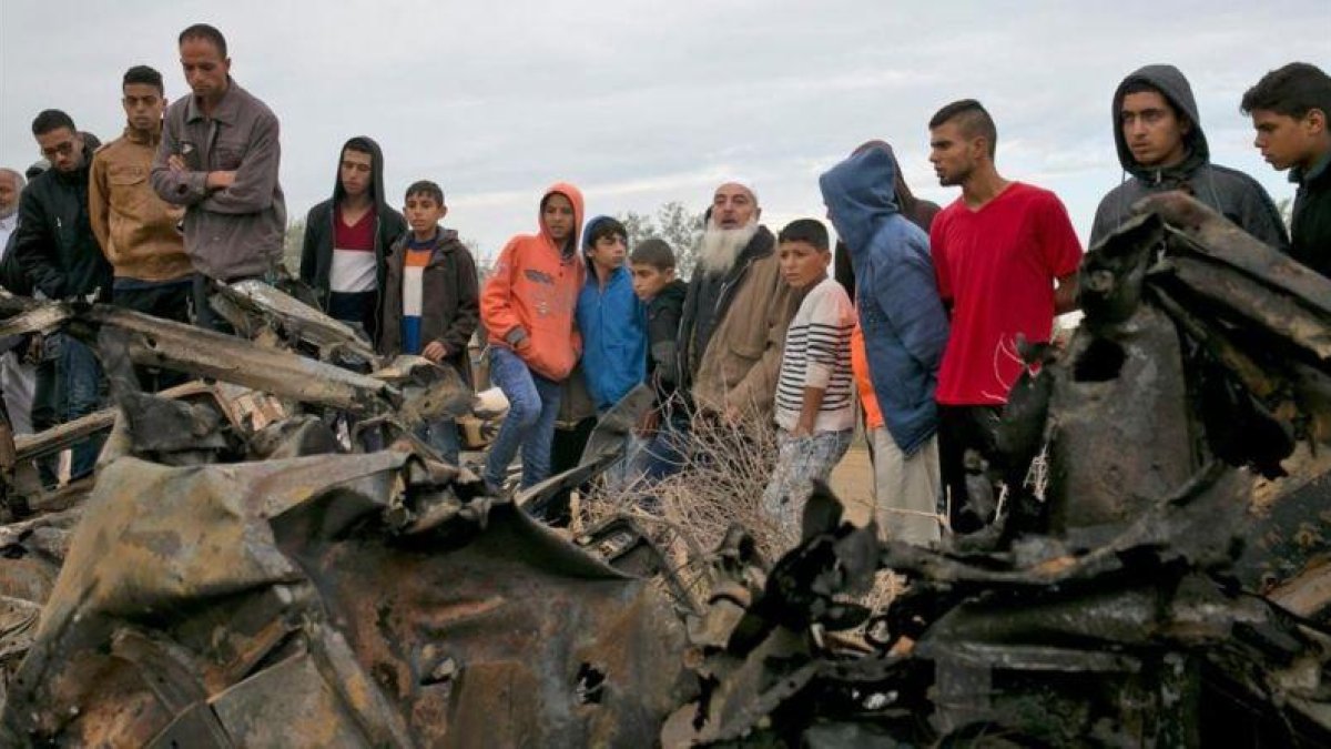 Unos palestinos permanecen junto a los restos de un automóvil destruido tras un ataque aéreo israelí en Khan Yunis, en el sur de la Franja de Gaza.-SAID KHATIB (AFP)