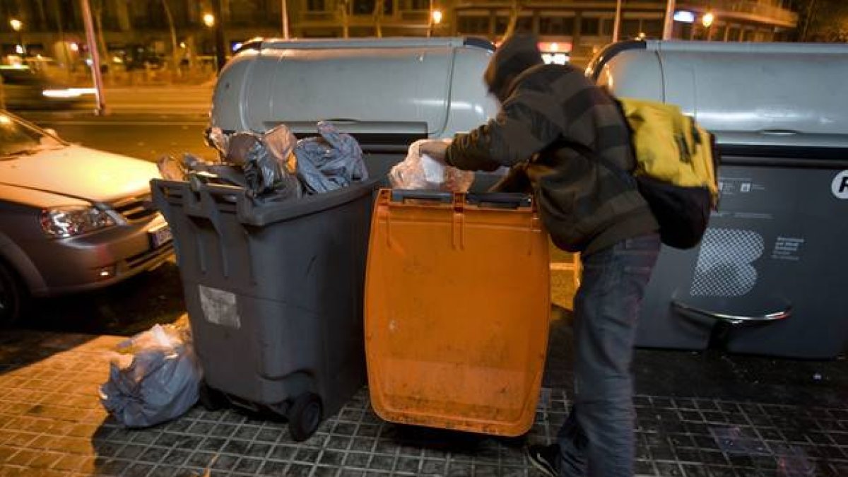 Un joven busca comida en un contenedor de basura orgánica, en Barcelona.-Foto: ALBERT BERTRAN