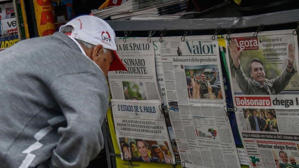 Un hombre lee en la prensa noticias sobre la victoria de Bolsonaro.-MIGUEL SCHINCARIOL / AFP