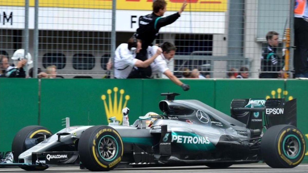 Hamilton celebra el triunfo en Alemania al paso frente a sus mecánicos.-AFP / THOMAS KIENZLE