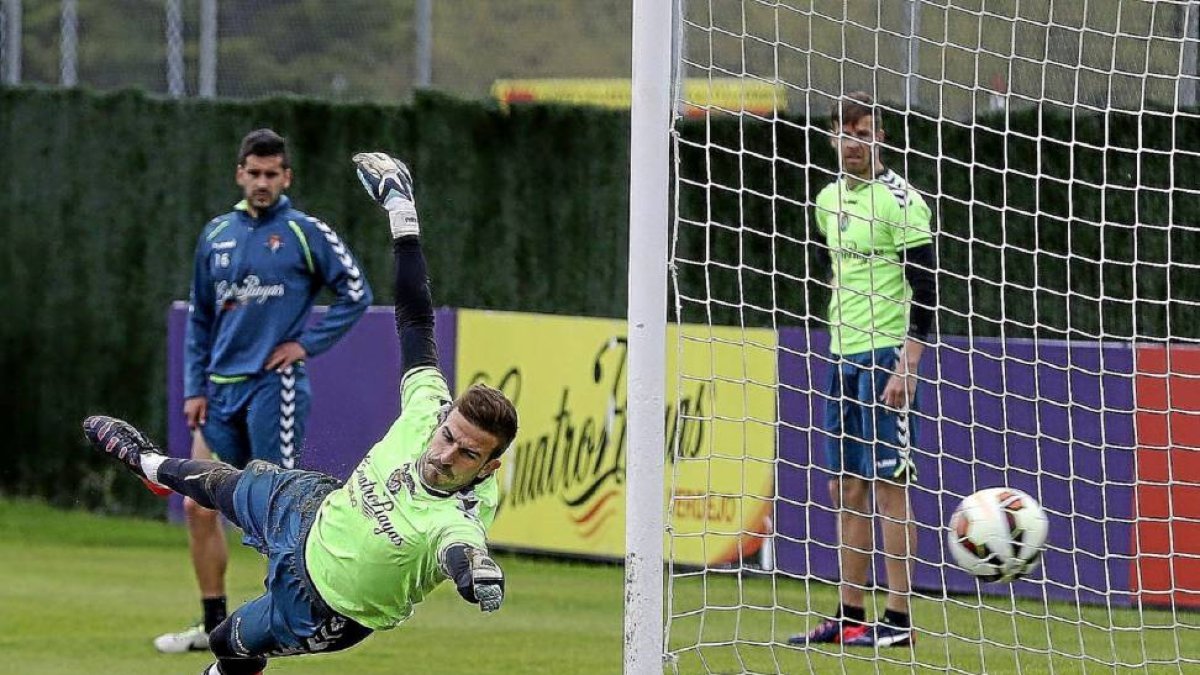 Javi Varas se lanza a su izquierda para desviar el balón durante el entrenamiento de ayer ante la mirada de Sastre y Chus Herrero-BALCAZA