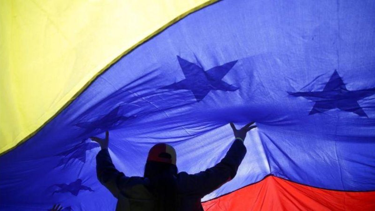 Una mujer sujeta una gran bandera de Venezuela.-ANDREA COMAS (AP)