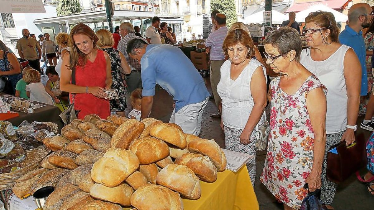 Unos clientes del Mercado frente a un puesto de pan ecológico.-J. M. LOSTAU