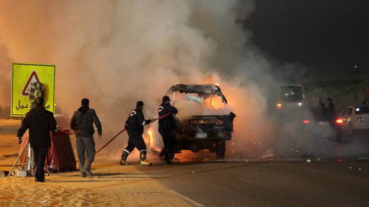 Dos bomberos tratan de apagar un coche incendiado durante los disturbios protagonizados por aficionados al fútbol en El Cairo el pasado 8 de febrero.-Foto: AFP/ STR