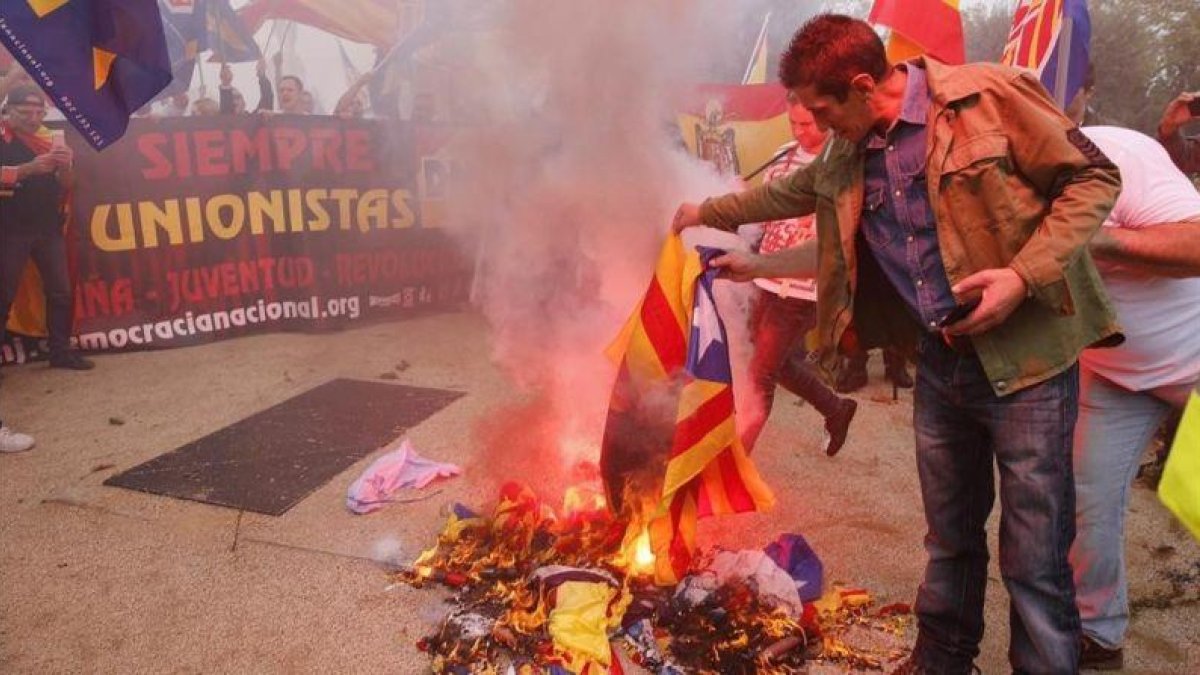 Varios manifestantes de la marcha ultra del 12-O en Barcelona queman una 'estelada'.-JOAN CORTADELLAS