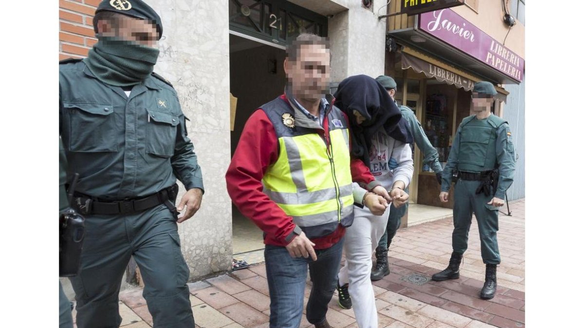 El detenido residente en la calle General Shelly, considerado como uno de los cabecillas, sale esposado de su casa.-M. Á. SANTOS /P. REQUEJO