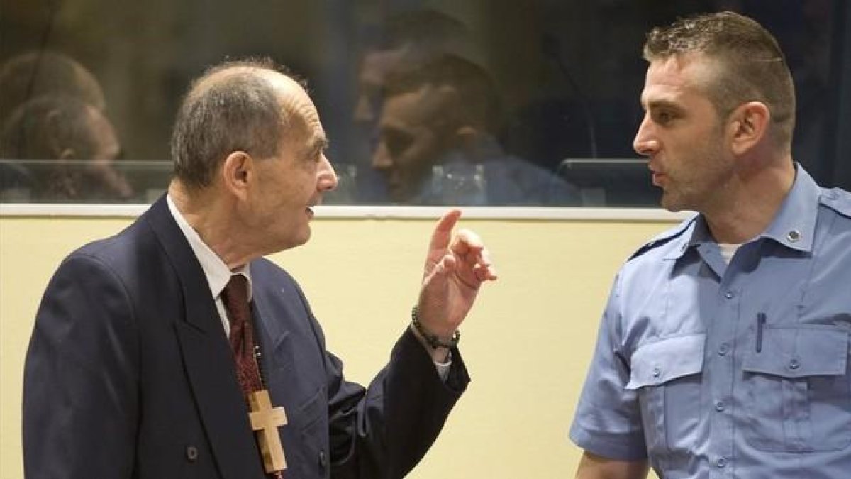 Tolimir (izq), condenado por la masacre de Srebrenica, habla con un guardia de seguridad de la ONU en el tribunal de La Haya, el pasado 8 de abril.-AP / PETER DEJONG