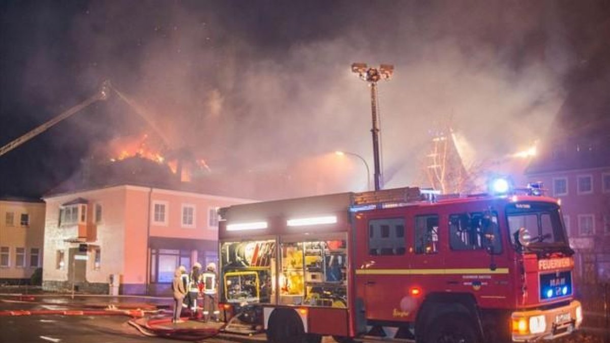 Los bomberos trabajan en la extinción del incendio del edificio que debía acoger a refugiados en Bautzen.-AFP / RICO LOEB